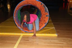 Young student crawling out of a colorful tunnel tube.