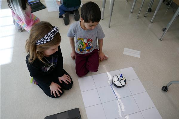 2 students working with robot on mat