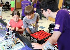 Three students working on a robotics assignment in a classroom